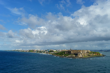 Scenic view of historic colorful Puerto Rico city in distance with fort in foreground from the sea (cruise ship)