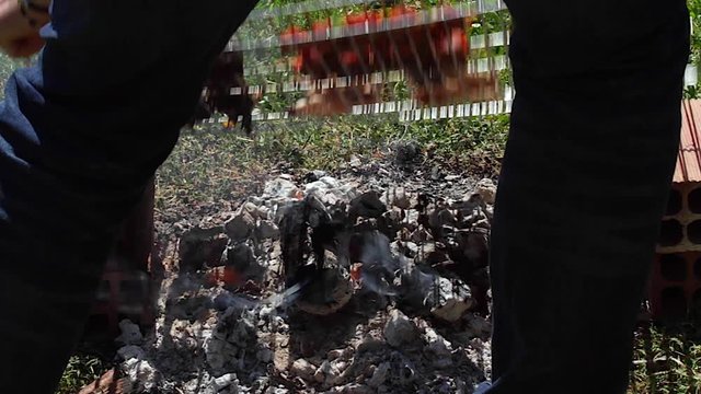 Dando vuelta a la parrilla al aire libre, con pinchos o brochetas de carne con pimiento verde, muslos de codorniz y morcilla con arroz