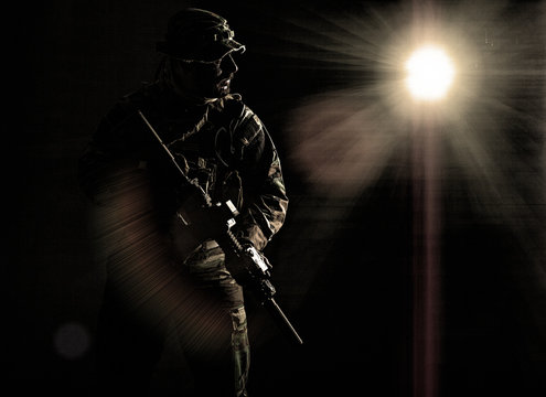 Bearded Special forces United States in Camouflage Uniforms studio shot half length. Holding weapons, wearing jungle hat, Shemagh scarf, he is ready to kill. Contour shot, backlit