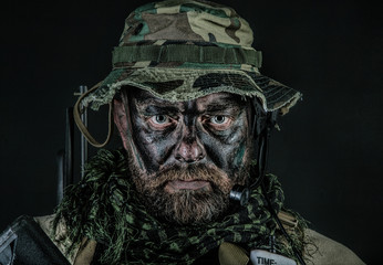 Fototapeta premium Special forces United States in Camouflage Uniforms studio shot. Wearing jungle hat, Shemagh scarf, painted face. Black background