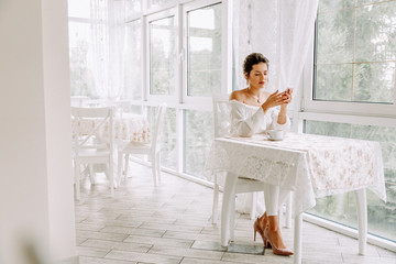 Woman using mobile phone in cafe. Female hand with smartphone and coffee.
