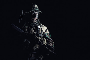 Fototapeta na wymiar Bearded Special forces United States in Camouflage Uniforms studio shot half length black background. Holding weapons, wearing jungle hat, Shemagh scarf, he is ready to kill. Backlit