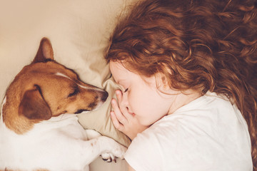 Sweet curly girl and dog is sleeping in night.