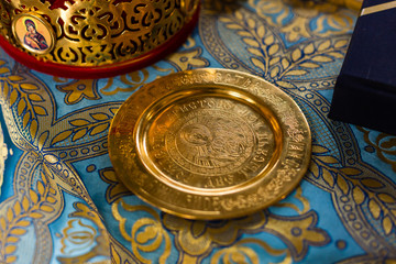 golden wedding rings on metal plate in church with holy water. wedding traditional ceremony. space for text