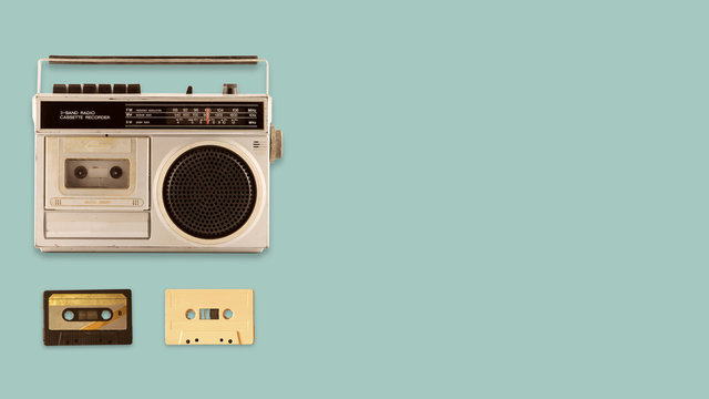 Radio cassette recorder and player with music tape cassette on color background. retro technology. flat lay, top view hero header. vintage color styles.