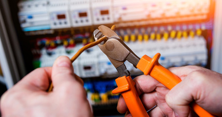 The man is repairing the switchboard voltage with automatic switches.