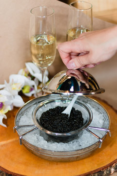 Black caviar in a silver icher with ice. Champagne is poured into the glass. Delicacy. An exquisite gift for the holiday. Food. VIP. Flower.