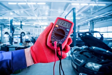 Auto mechanic uses a voltmeter to check the voltage level.