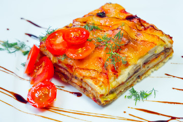 Lasagna with tomatoes on a white plate