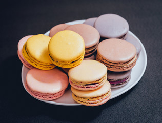 Colorful macaroons. Sweet macarons on retro dark background.