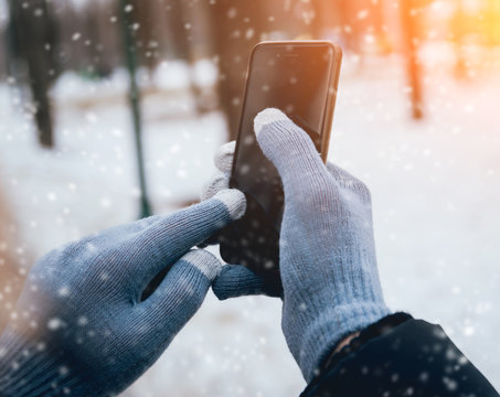 Man Using Smartphone In Winter With Gloves For Touch Screens