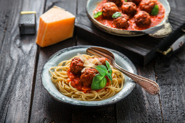 Spaghetti with meatballs and tomato sauce and basil, rustic style, selective focus