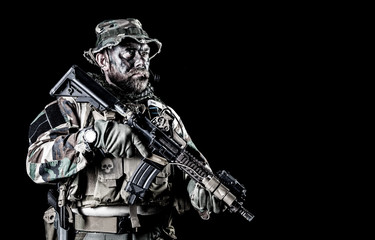 Bearded Special forces United States in Camouflage Uniforms studio shot half length black background. Holding weapons, wearing jungle hat, Shemagh scarf, he is ready to kill. Backlit