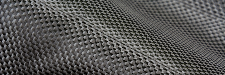 Black carbon fiber composite raw material close up background