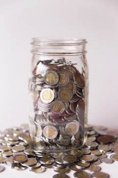 glass jar with many mexican pesos coins