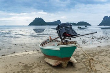 Obraz premium alone Fishing boat on the beach cloudy background