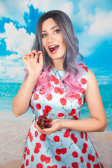 joyful young pin up girl eating sweet cherry standing alone