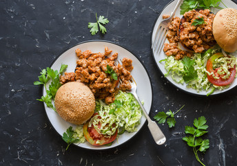 Sausage pork burger with salad on dark background, top view. Flat lay