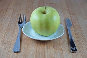 Apple with fork and knife in a dish