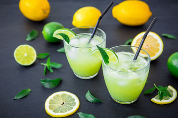 Citrus refreshing lemonade with limes, ice and lemons in glasses