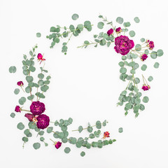 Floral frame of rose flowers and eucalyptus branches on white background. Flat lay, top view