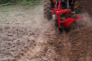 Naklejka premium Tractor in the field plows the earth
