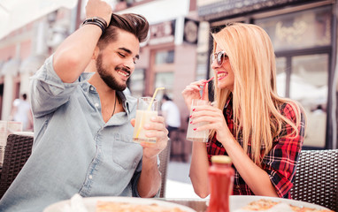 Beautiful young couple sitting in the cafe and eating pizza. Consumerism, food, lifestyle concept