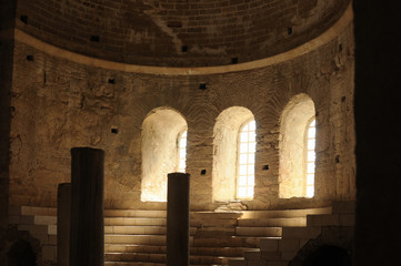 The rays of sunlight penetrate inside the ancient temple through the arched windows.