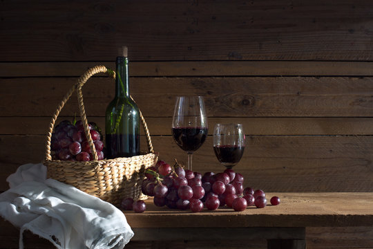 Still Life image of Fresh grapes and wine bottle in the brown basket with glass of wine