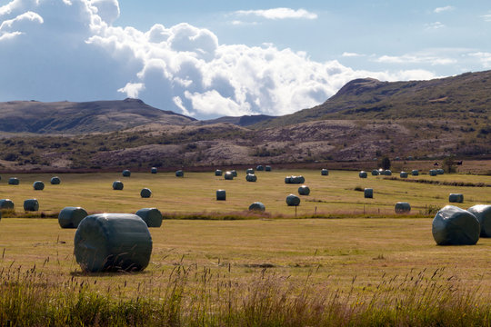Iceland - landscape with mountains, baled silage, hay, green grass. blue sky and clouds.