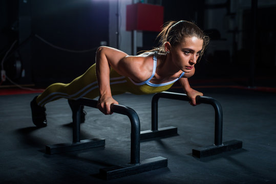 Parallettes woman parallel bars workout exercise at dark gym