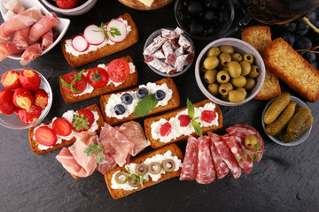 Italian antipasti wine snacks set. Cheese variety, Mediterranean olives, pickles, Prosciutto di Parma, tomatoes and wine in glasses. Spanish tapas