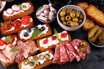 Italian antipasti wine snacks set. Cheese variety, Mediterranean olives, pickles, Prosciutto di Parma, tomatoes and wine in glasses. Spanish tapas
