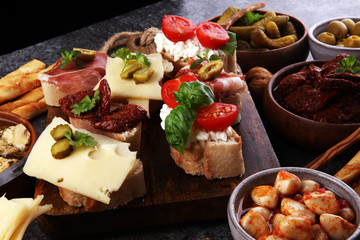 Italian antipasti wine snacks set. Cheese variety, Mediterranean olives, pickles, Prosciutto di Parma, tomatoes, artichokes and wine in glasses