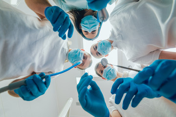 Four dentist in uniform perform dental implantation operation on a patient at dentistry office