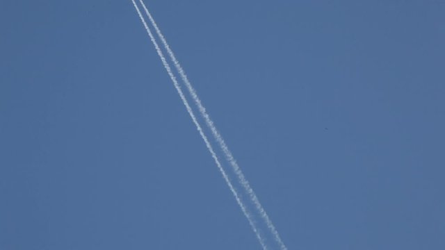 The flying plane against the background of the blue sky draws a double strip