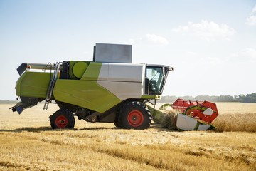 Obraz premium Working combine harvester in a wheat field. Agricultural background.