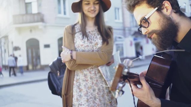 Handsome guy is playing acustic guitar while girl listening
