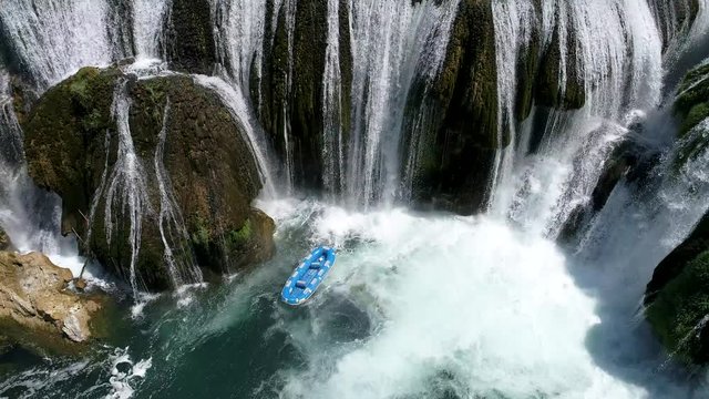aerial .flying over rafting boat while skipper is throwing it  from waterfall.