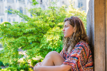 Side profile of young woman sitting on windowsill by garden