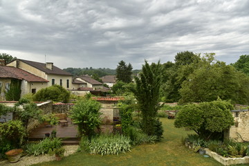 Fototapeta na wymiar Passage d'un front orageux au dessus des jardins et des maisons rustiques au village de Champagne, au Périgord Vert 