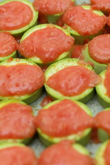 Sliced zucchini topped with tomato sauce before baking
