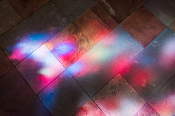 Colorful reflections of stained glass murals on stone ground closeup - obrazy, fototapety, plakaty