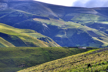 View of a green mountain range, part of the Ecuadorian Andes, with a beautiful sunny and cloudy sky. Cayambe, Ecuador.