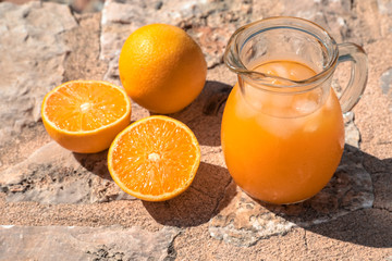 Fresh orange juice and oranges isolated on a stone surface.