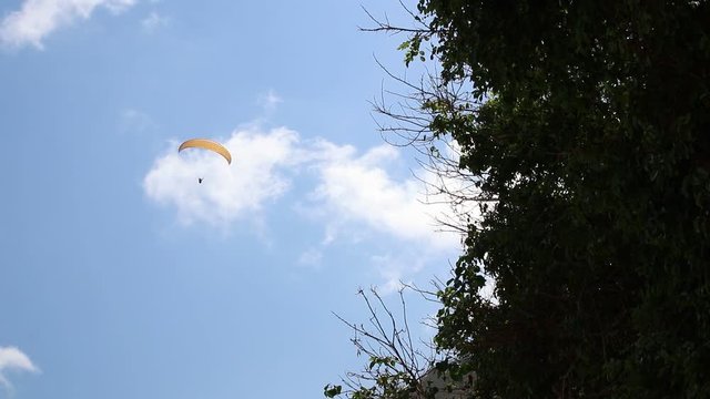 Paraglider with paraplane slowly flying in blue cloudless sky. Shot made on a tropical island of Bali, Indonesia.