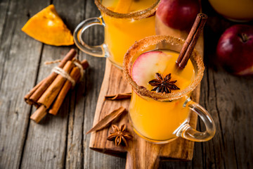 Halloween, Thanksgiving. Traditional autumn, winter drinks and cocktails. Spicy hot pumpkin sangria, with apple, cinnamon, anise. On old rustic wooden table, in glass mugs. Selective focus copy space