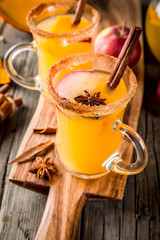 Halloween, Thanksgiving. Traditional autumn, winter drinks and cocktails. Spicy hot pumpkin sangria, with apple, cinnamon, anise. On old rustic wooden table, in glass mugs. Selective focus copy space