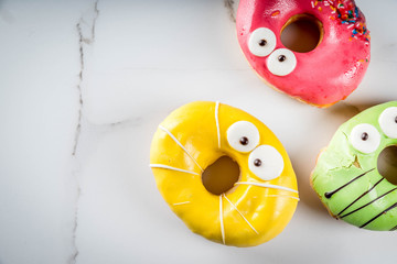 Ideas for children treats on Halloween. Colorful  donuts in the form of monsters with eyes, green,...