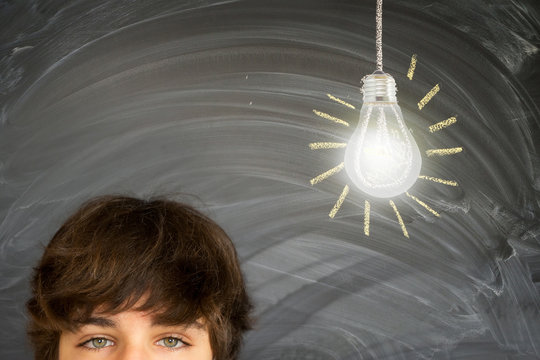 Eyes of teenager boy against getting an idea blackboard with glowing lightbulb background